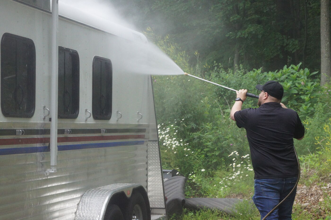 Happy Camper technician pressure washing the side of a horse trailer