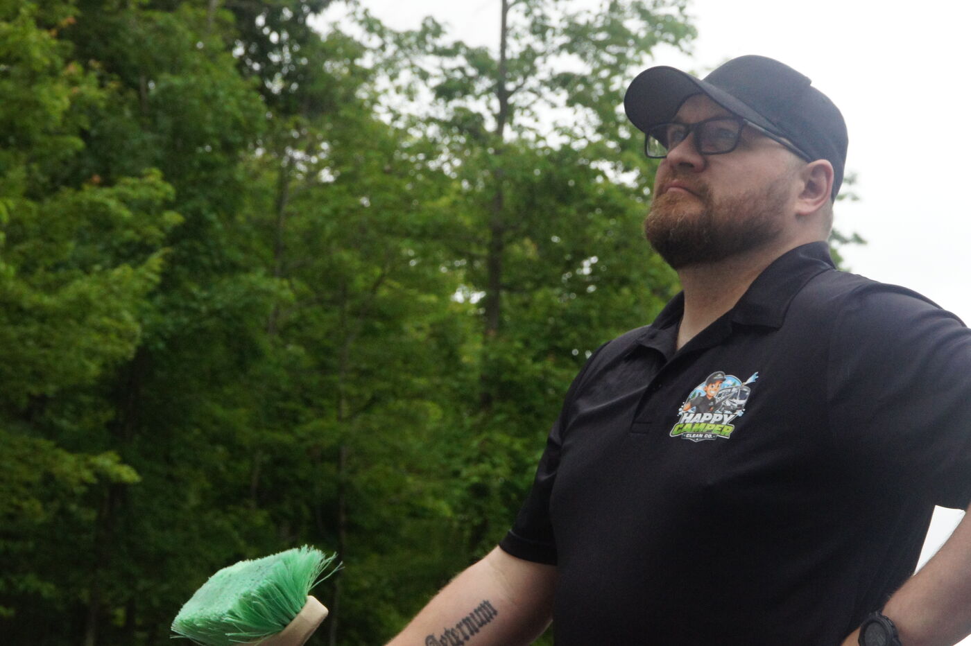 Happy Camper crew member with a cleaning brush ready to work on an RV
